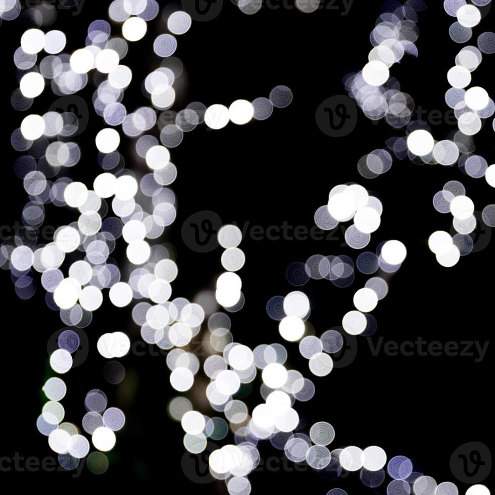 abstraktes bokeh der weißen stadtlichter auf schwarzem hintergrund. defokussiert und verschwommen viele runde licht foto