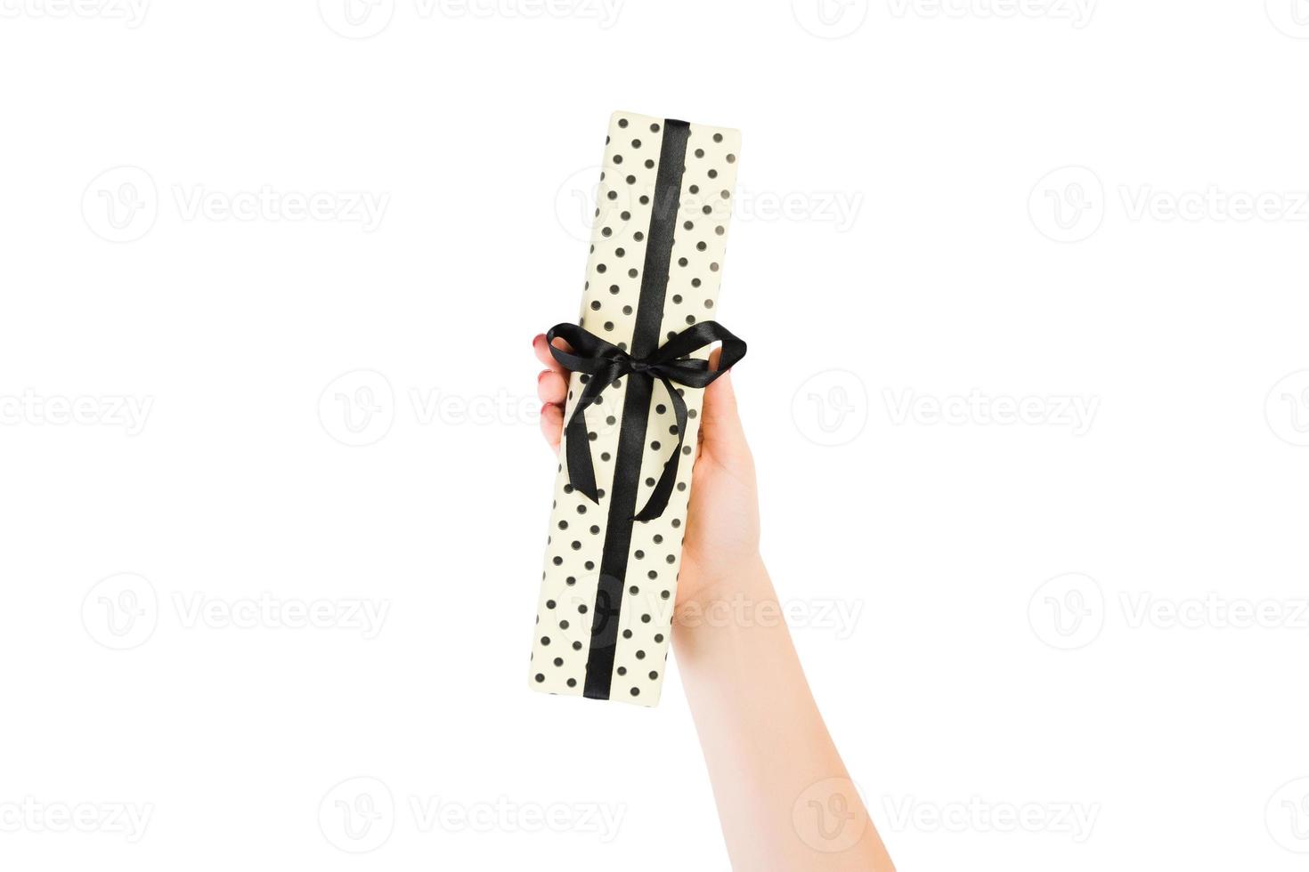 frauenhände geben eingewickeltes weihnachts- oder anderes handgemachtes geschenk in gelbem papier mit schwarzem band. isoliert auf weißem Hintergrund, Ansicht von oben. Thanksgiving-Geschenkbox-Konzept foto