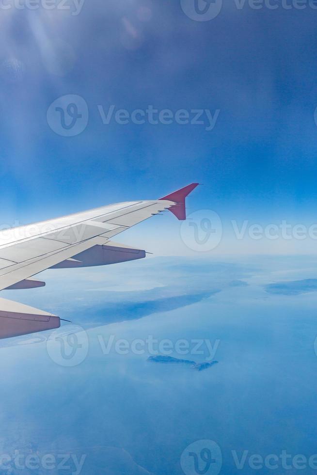 Flugzeugflügel auf den Wolken, fliegt auf dem Stadthintergrund foto