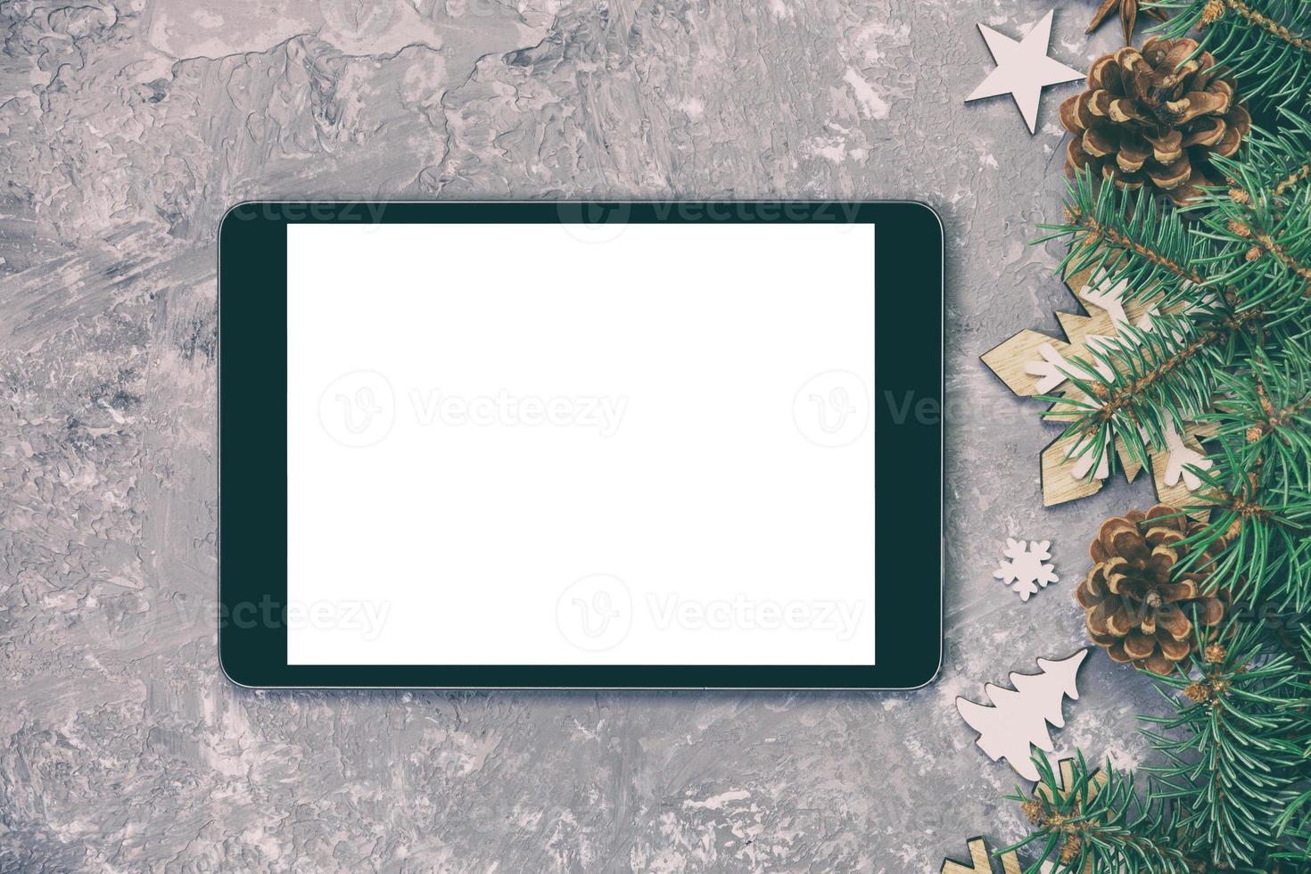 digitales tablet-modell mit rustikalen weihnachtlichen grauen zementhintergrunddekorationen für die app-präsentation vintage, getönt. draufsicht mit kopierraum foto