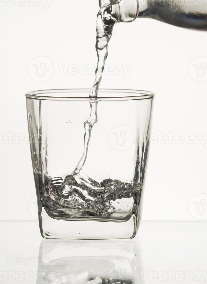 Wasser aus der Flasche ins Glas gießen foto