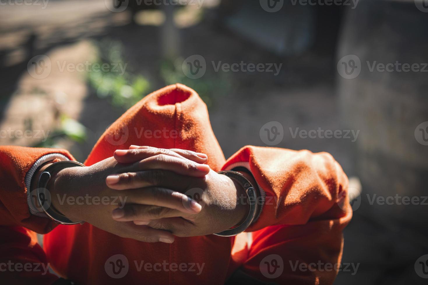 verzweifelter krimineller, der in handschellen auf dem boden sitzt. sie wurde wegen Raubes festgenommen. foto