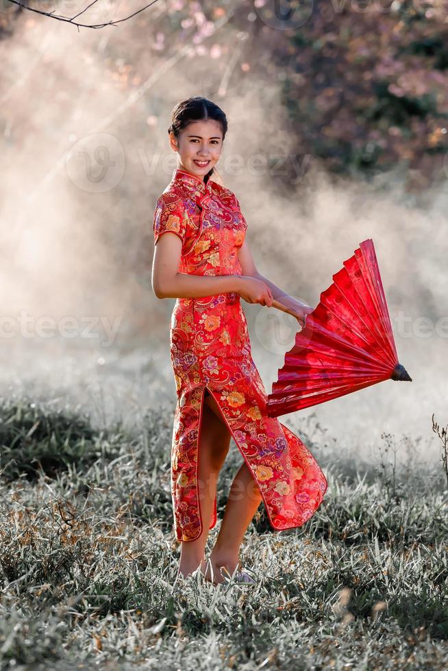 reise, urlaub in japan konzept, junge asiatin, die roten traditionellen japanischen kimono trägt und morgens regenschirm im park hält. foto