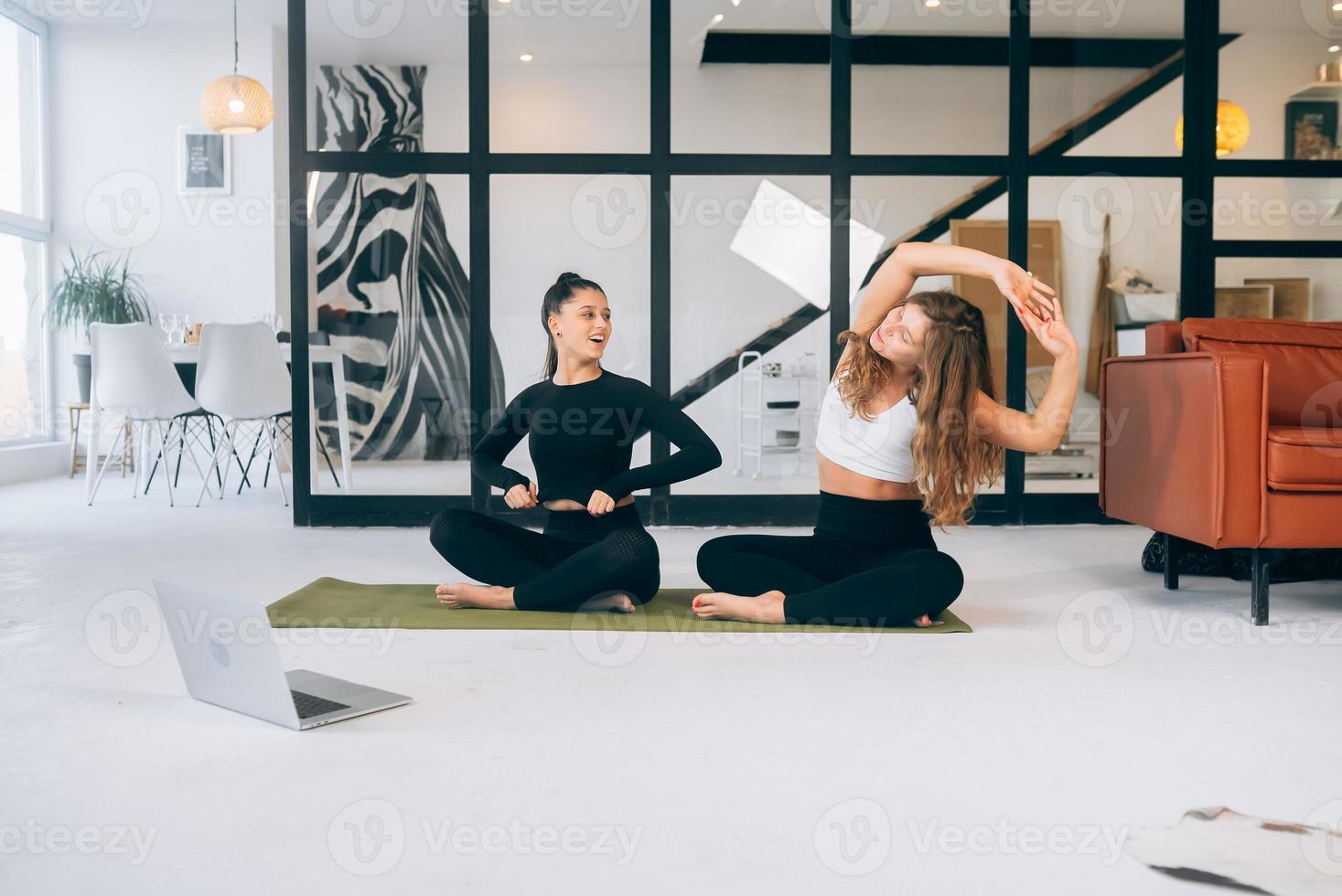 Zwei junge Frauen meditieren zu Hause in Lotus-Pose foto