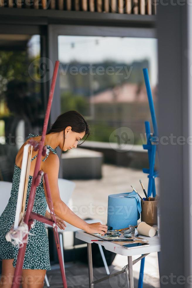 junge künstlerin steht nahe tisch mit einer palette foto