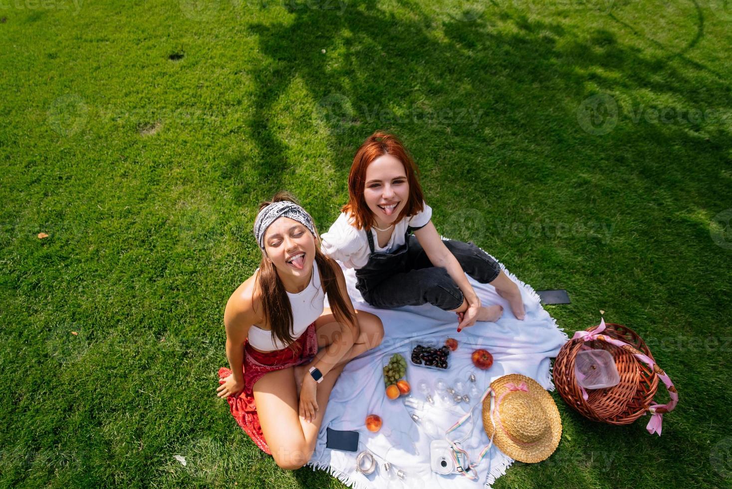 zwei frauen, die zusammen picknicken, sitzen auf dem plaid foto