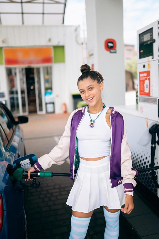 Frau, die ihr Auto an einer Tankstelle mit Kraftstoff befüllt foto