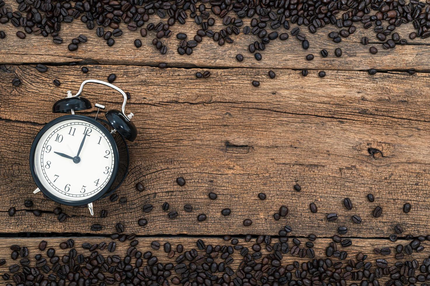 Wecker und Kaffeebohnen auf dem Schreibtisch foto