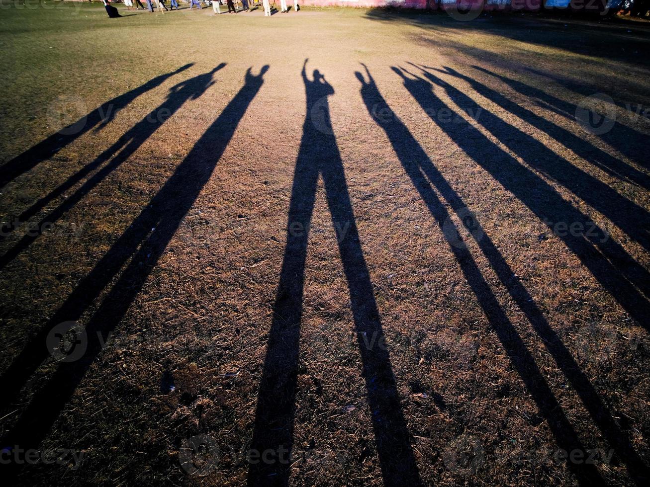Freunde, die abends auf einem Schulfeld lange Schatten erzeugen foto