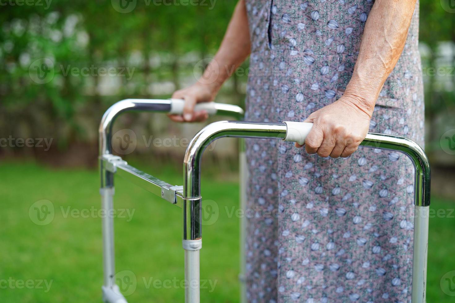 asiatische ältere Frau mit Behinderung, Patient zu Fuß mit Rollator im Park, medizinisches Konzept. foto