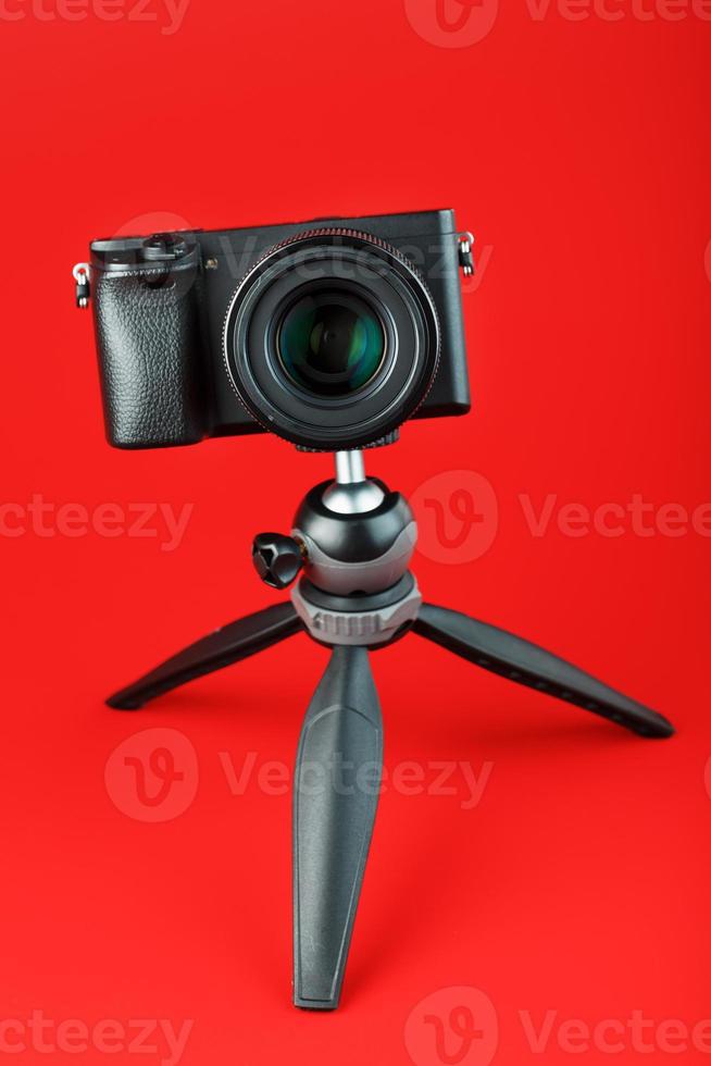professionelle Kamera auf einem Stativ, auf rotem Hintergrund. Nehmen Sie Videos und Fotos für Ihren Blog, Reportage auf
