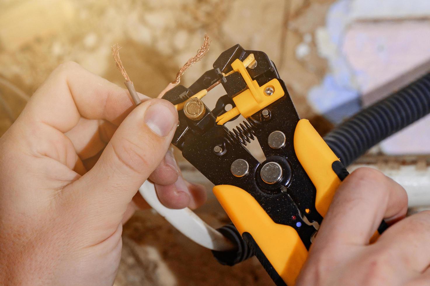 Verwendung des Werkzeugs zum Entfernen der Isolierung zum Entfernen des Endes eines elektrischen Kabels während der Reparatur und Aktualisierung der elektrischen Verkabelung im elektrischen Hausnetz, Elektroarbeiten. foto