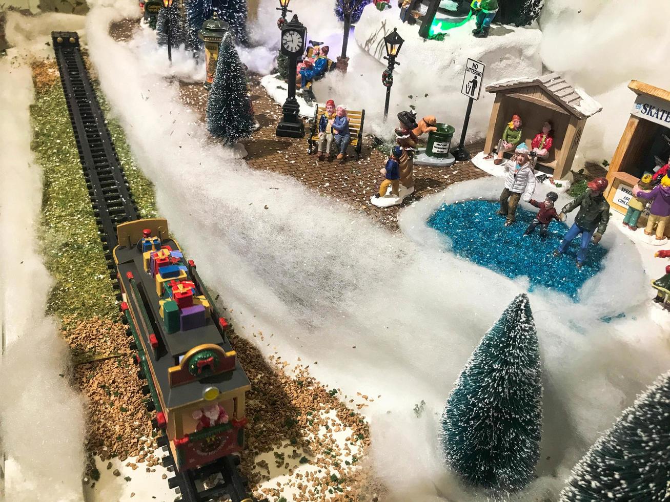 Landschaft des neuen Jahres. Spielzeugminiatur für die Vitrine. süße Vitrine, handgemachte Komposition. In der Mitte fährt ein Zug, die Waggons sind mit Schnee bedeckt foto