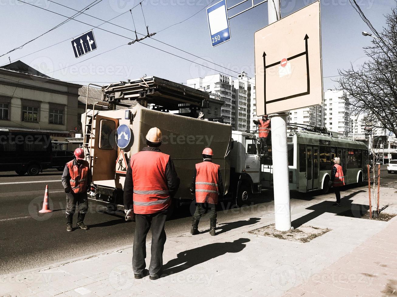 Straßenarbeiter in Roben, Overalls und Bauhelmen arbeiten an der Reparatur der Straße auf der Straße, der Straße foto