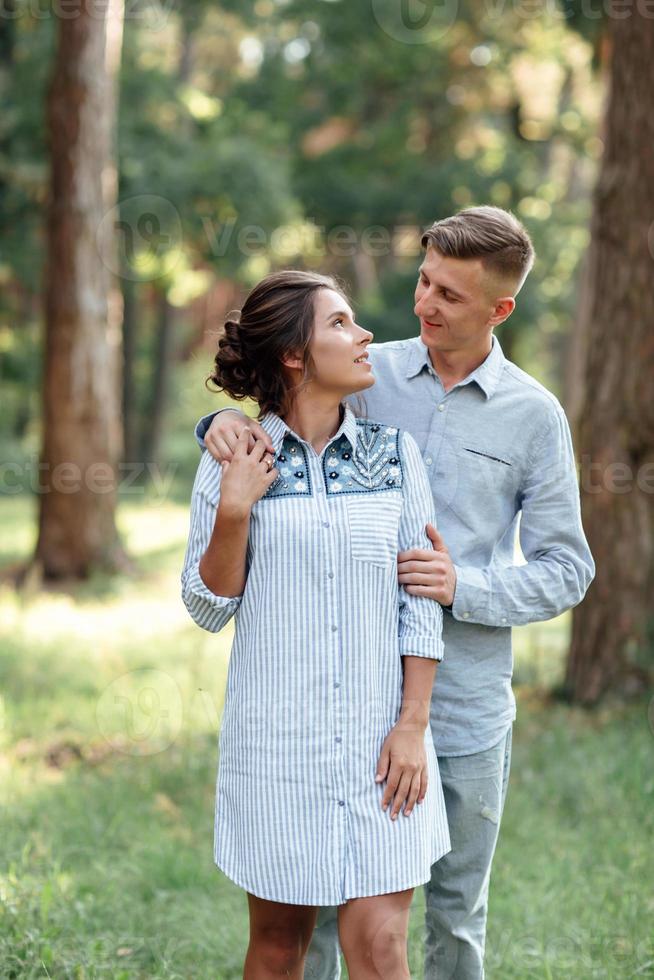 Fröhliche junge Frau und Mann umarmen sich im Sommerpark im Freien. Dating und romantischer Urlaub. Verliebtes Paar sieht sich an einem sonnigen Tag sanft an. Liebe und Beziehungen zwischen jungen Menschen foto