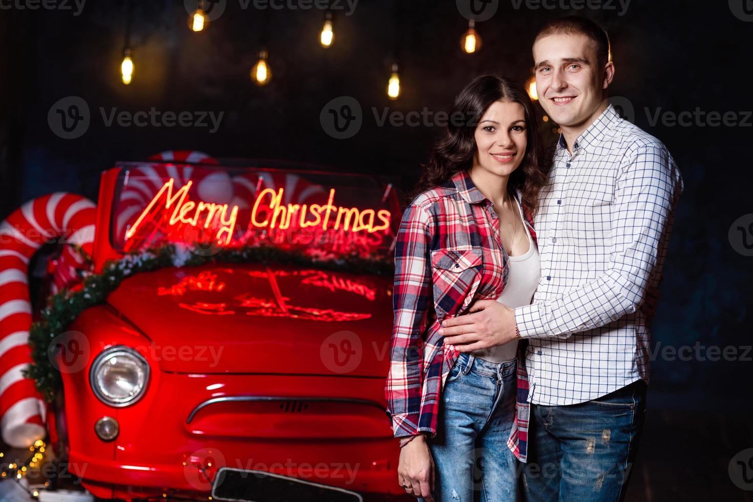 Schönes verliebtes Paar, das sich vor dem Hintergrund von leuchtenden Lichtern und Retro-Autos umarmt. Studio-Porträtfoto. Valentinstag. liebendes Paar. Valentinstag. Weihnachtsfeiertage foto