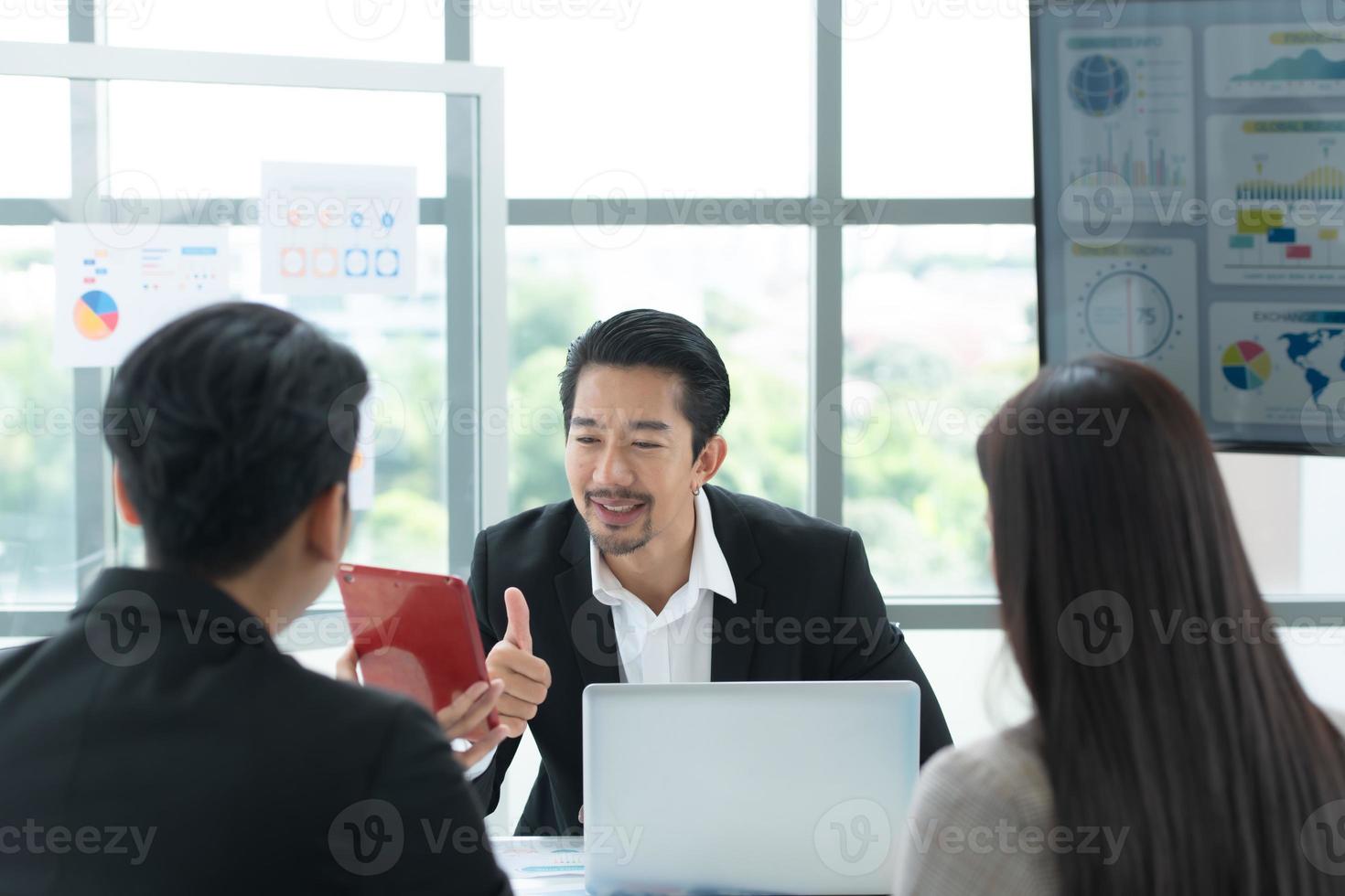 eine Gruppe junger asiatischer Unternehmer. Das Top-Management trifft sich, um die Aktieninvestitionsdaten des Teams in einem Besprechungsraum mit Tageslicht zu überprüfen foto