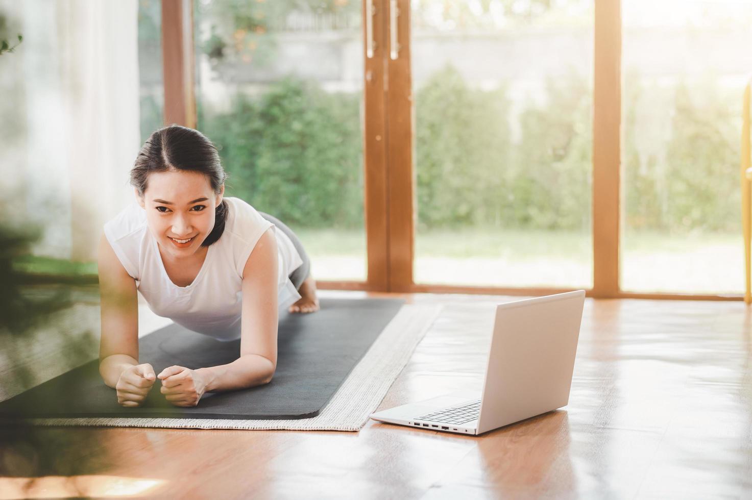 Frau, die Planke auf einer Yogamatte tut foto