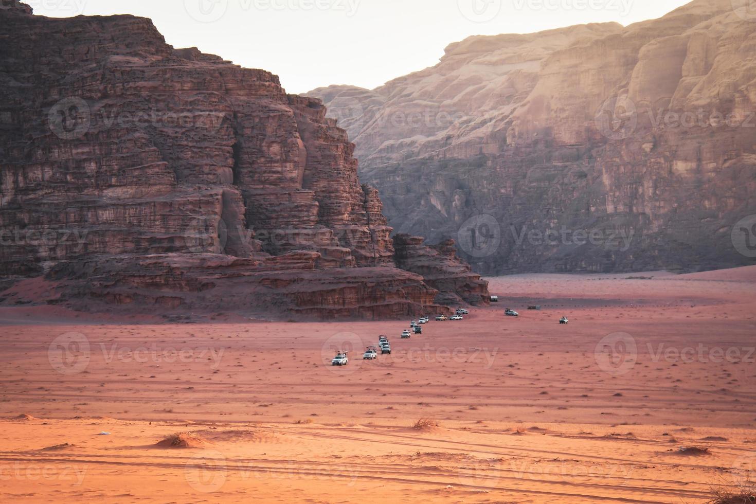 wadi rum wüstenlandschaft mit einer reihe von allradfahrzeugen fahren vom aussichtspunkt des sonnenuntergangs auf einer organisierten sonnenuntergangstour in jordanien foto