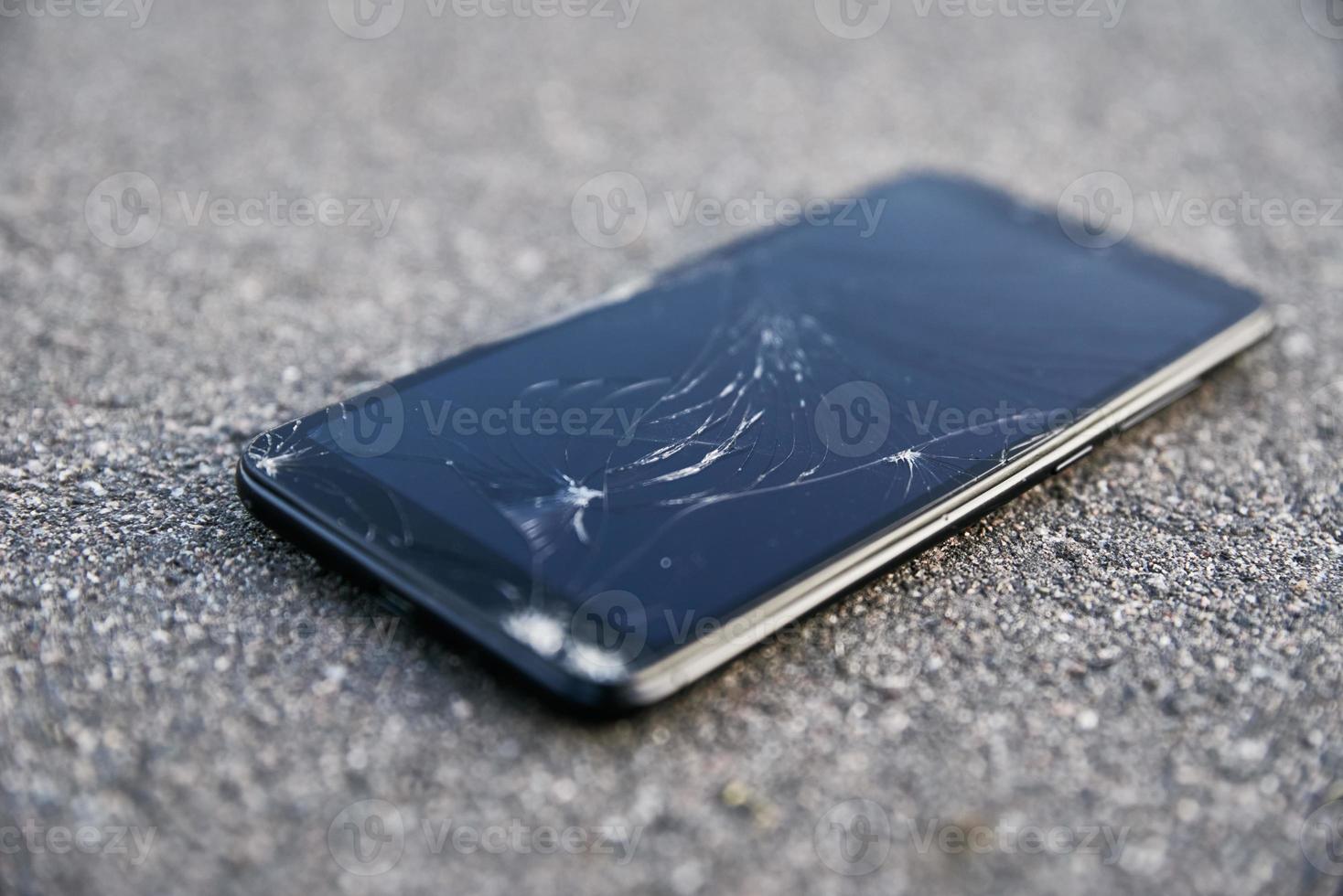 Beschädigtes Smartphone mit defektem Touchscreen auf Asphalt foto