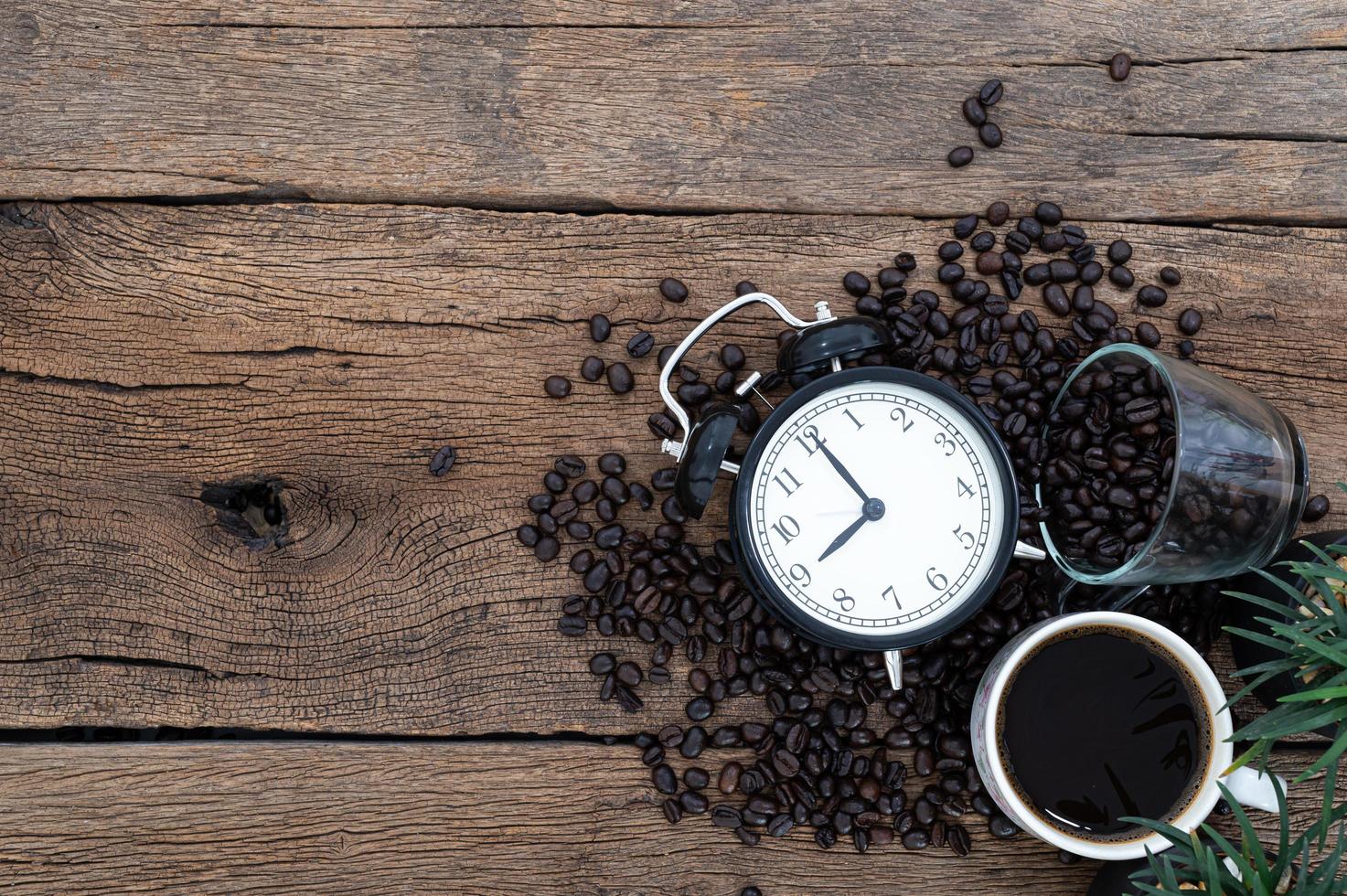 Wecker, eine Tasse Kaffee und Kaffeebohnen auf dem Schreibtisch foto