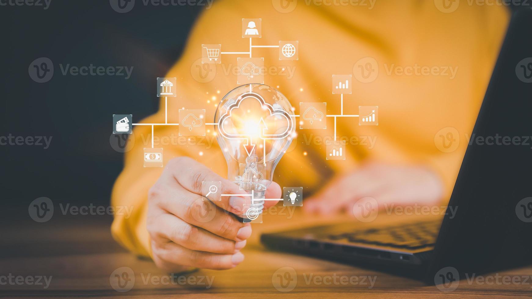 Mann, der eine Glühbirne hält, während er am Computer arbeitet, um zu denken und neue Ideen zu entwickeln. Geschäftsanwendungstechnologie für globale Internetverbindungen und digitales Marketing, Finanzen und Bankwesen. foto