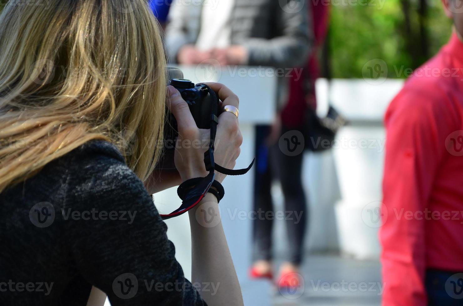 Hochzeitsfotograf im Prozess seiner Arbeit. professioneller fotograf schießt eine hochzeitszeremonie. Ein junges Mädchen schaut in den Sucher der Kamera foto