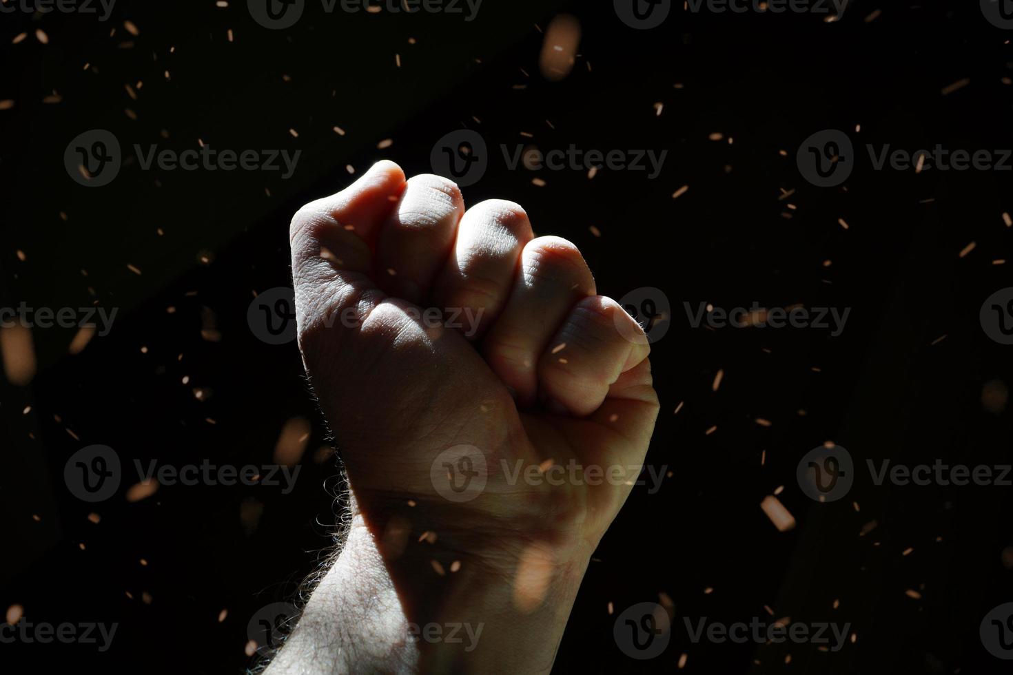Mann mit der Hand nach oben gestikulierend im Schatten, dunkler Hintergrund foto