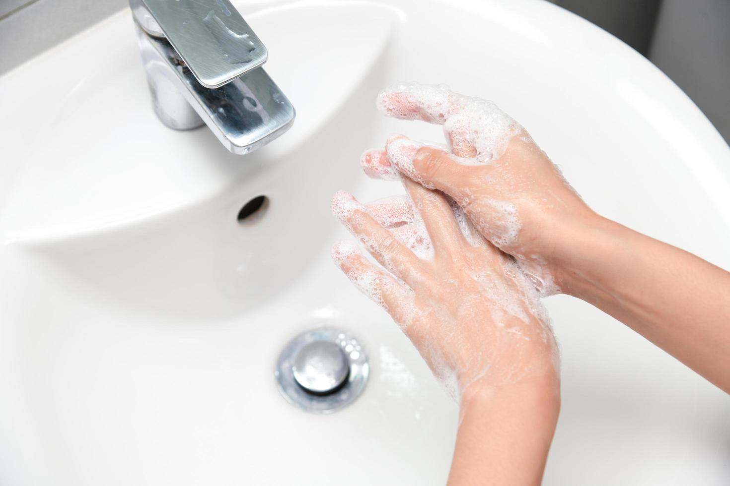 Frau benutzt Seife und wäscht sich die Hände unter dem Wasserhahn. foto