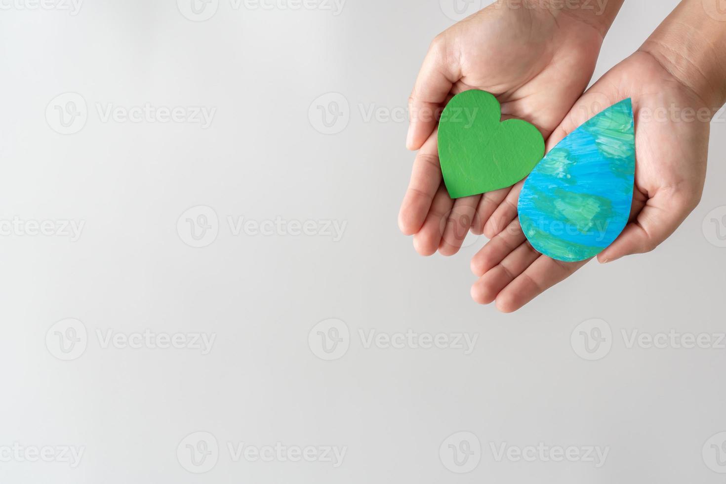 Erwachsene Hände, die den Wassertropfen und das grüne Öko-Herz auf weißem Hintergrund halten. foto