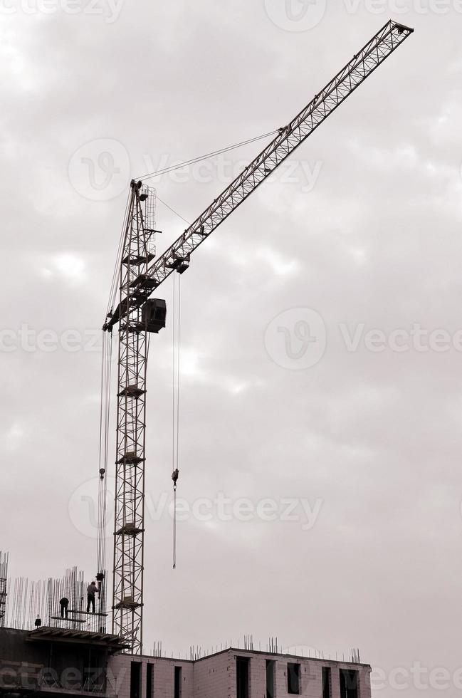 arbeitende hohe Kräne im Inneren mit hohen Gebäuden im Bau vor einem strahlend blauen Himmel. Fortschritt der Kran- und Bauarbeiten. Retro-Ton foto