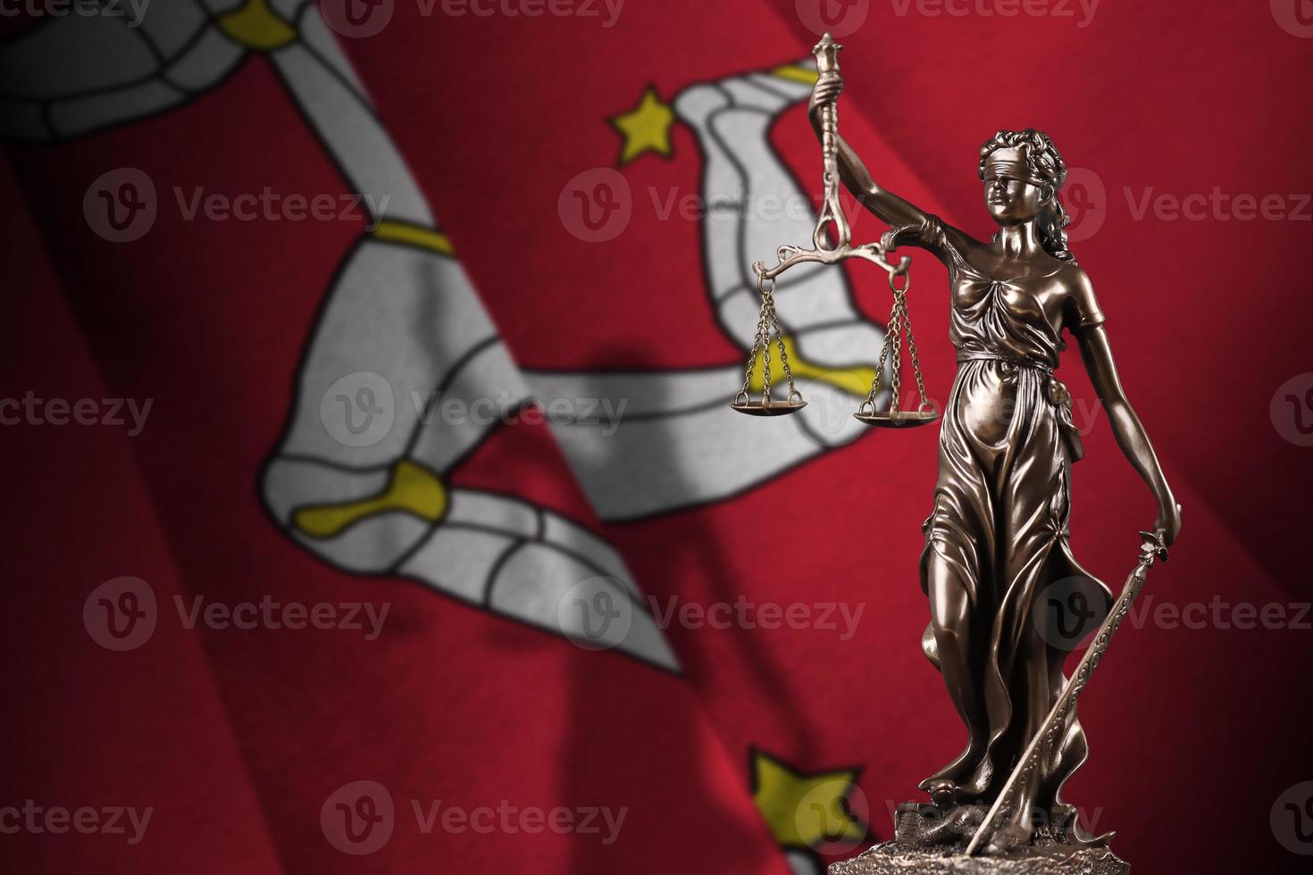 isle of man-flagge mit statue der dame justiz und gerichtswaage im dunklen raum. Konzept von Urteil und Bestrafung foto