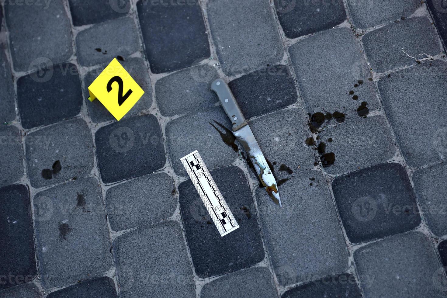 beweis mit gelbem csi-marker zur beweisnummerierung auf dem wohnhinterhof am abend. Tatortuntersuchungskonzept foto