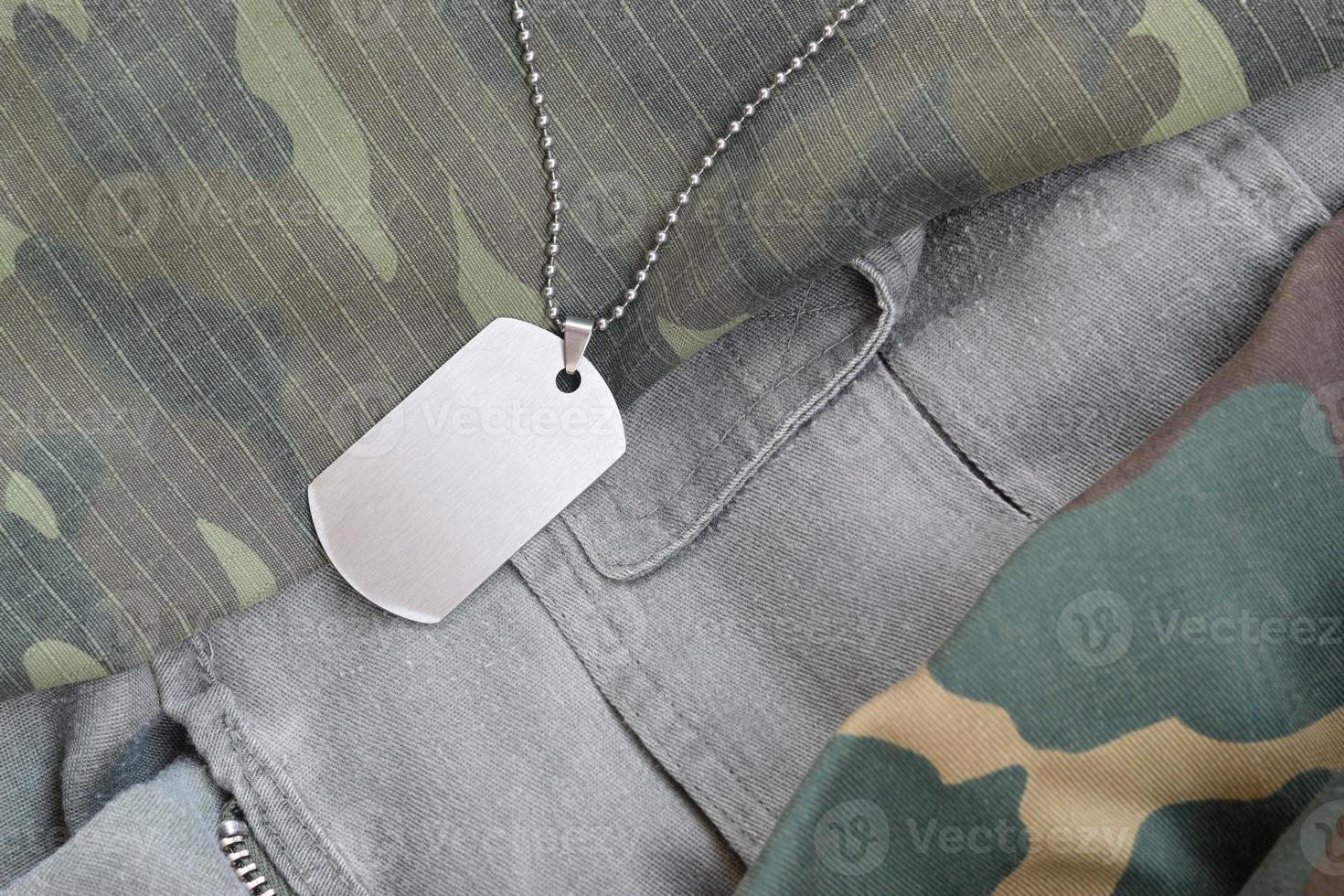 silberne Militärperlen mit Erkennungsmarke auf verschiedenen Camouflage-Ermüdungsuniformen foto