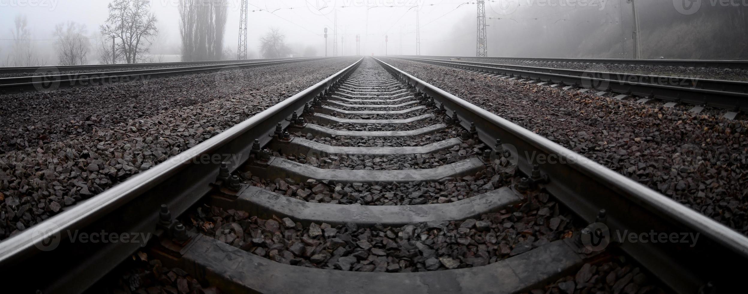 die Bahngleise an einem nebligen Morgen. viele schienen und schwellen gehen in den nebligen horizont. Fisheye-Foto mit erhöhter Verzerrung foto