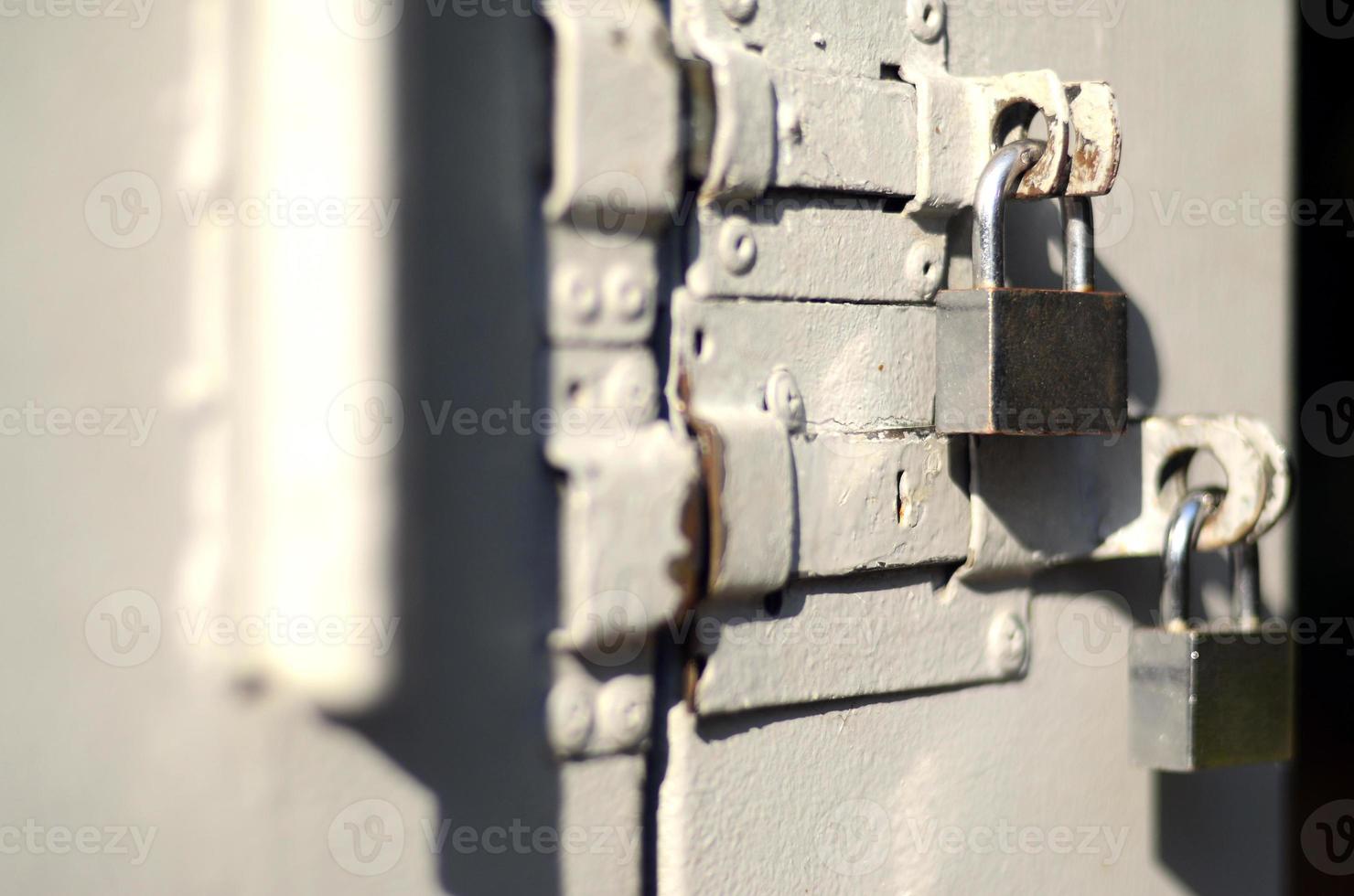 Ein Foto des Fragments zeigt eine Metalltür mit zwei quadratischen Vorhängeschlössern. selektiver fokus mit geringer schärfentiefe