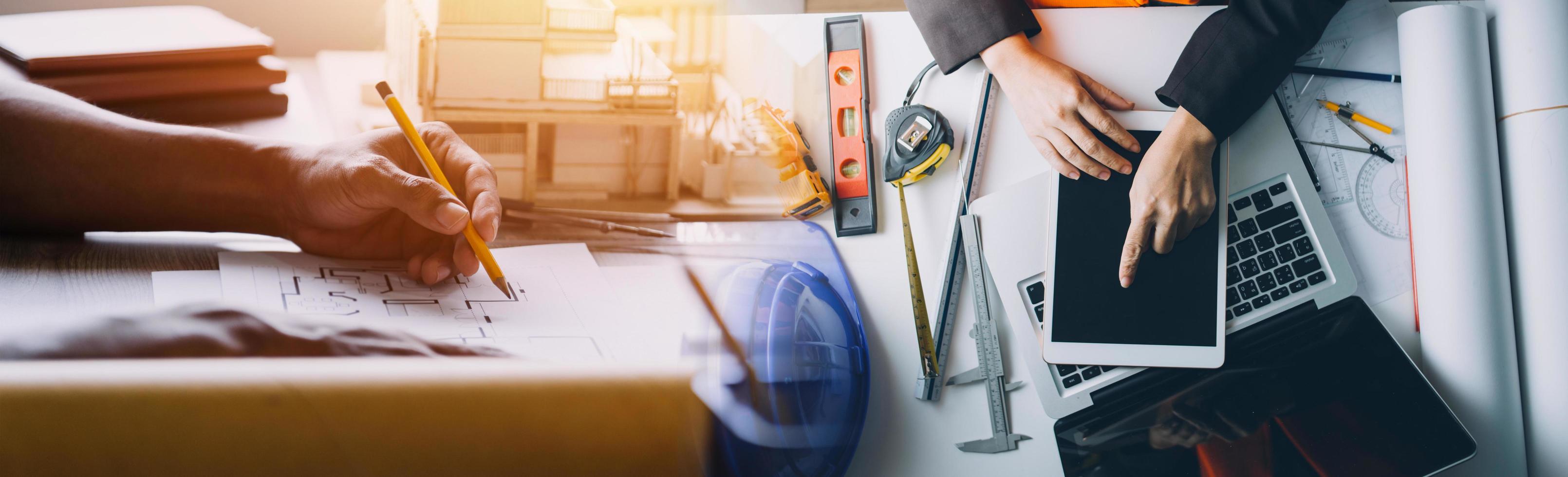 Zwei Kollegen diskutieren über Datenverarbeitung und Tablet, Laptop mit einem Architekturprojekt auf der Baustelle am Schreibtisch im Büro foto