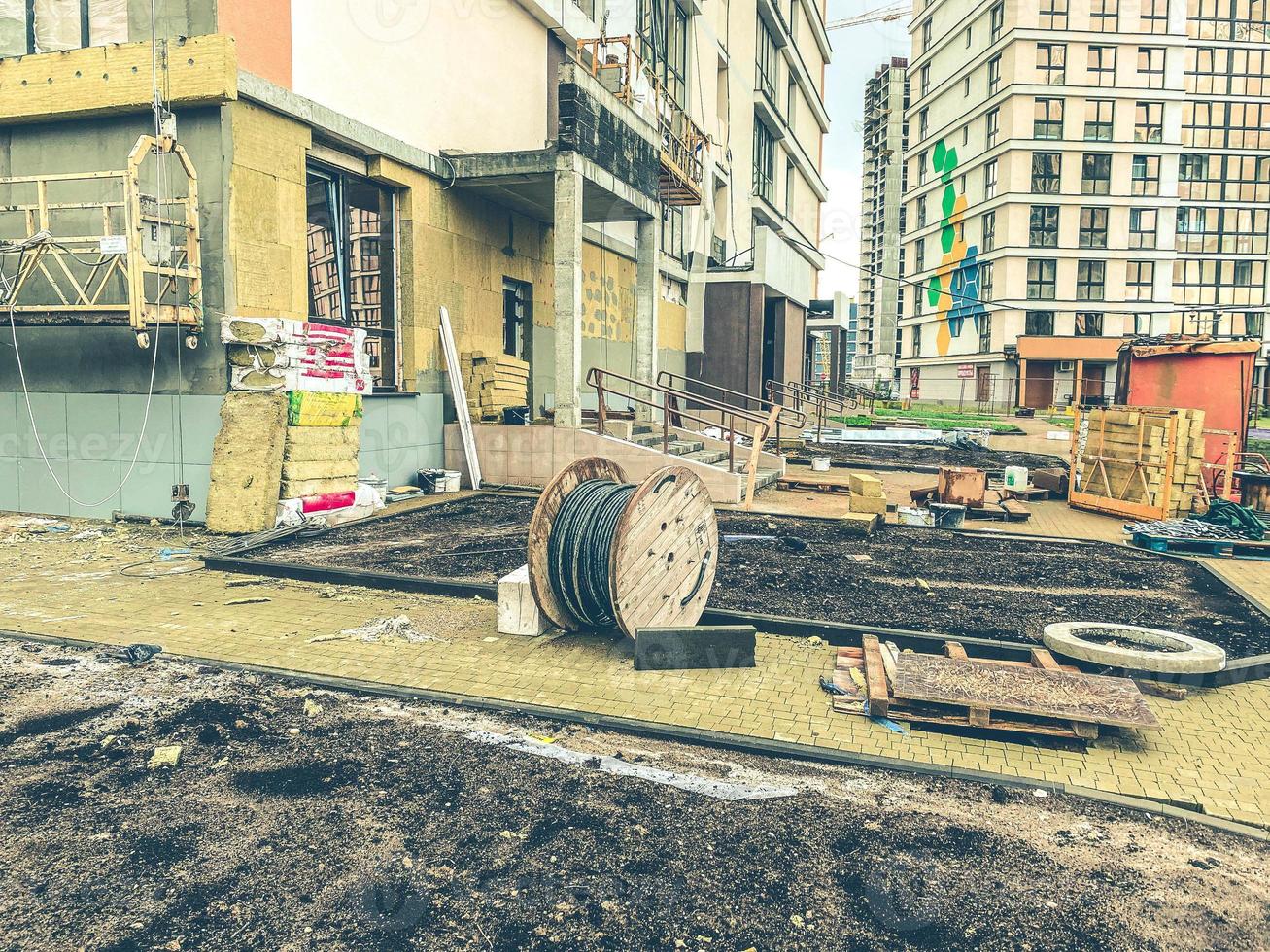 Bau eines neuen Viertels in der Stadt. Errichtung von hohen, mehrstöckigen Häusern aus Betonblöcken. Bau von Blumenbeeten, Fußwegen, Schaffung von Infrastruktur foto