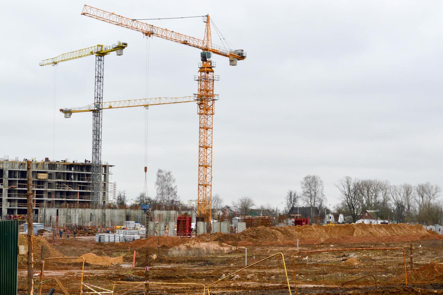 Bau eines neuen Mikrobezirks mit hohen Häusern, Neubauten mit ausgebauter Infrastruktur mit Hilfe großer Industriekräne und professioneller Baumaschinen in einer Großstadt foto