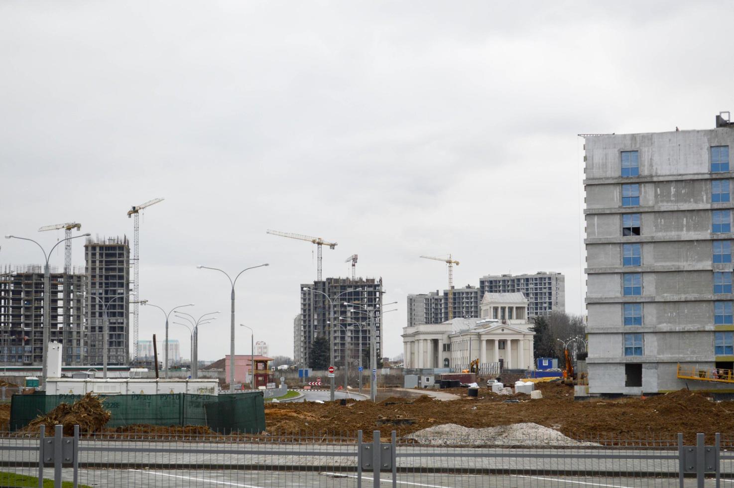 Bau eines neuen Mikrobezirks mit hohen Häusern, Neubauten mit ausgebauter Infrastruktur mit Hilfe großer Industriekräne und professioneller Baumaschinen in einer Großstadt foto