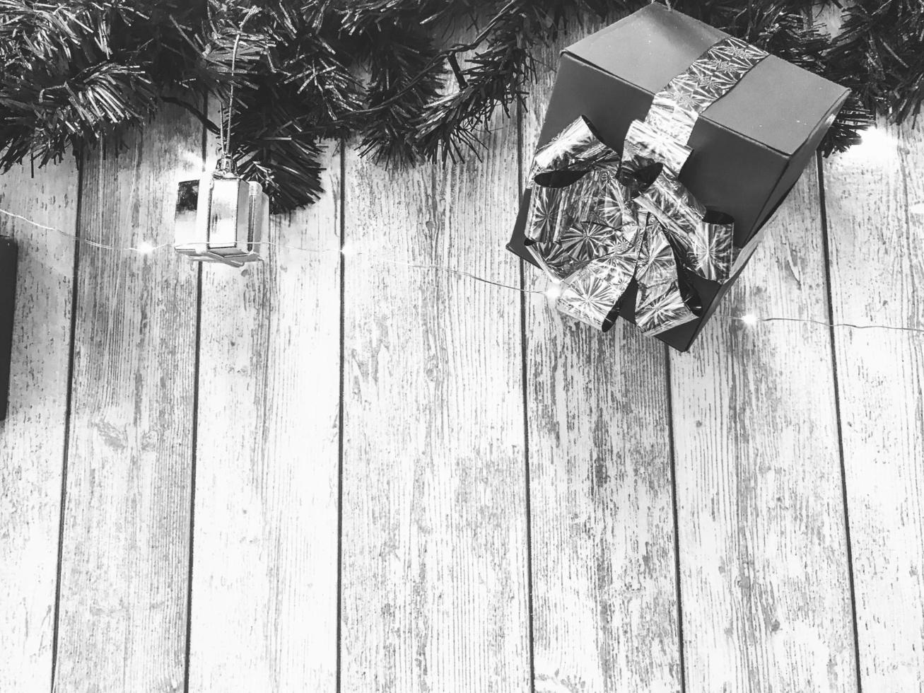 kleine niedliche schwarz-weiße weihnachtsgeschenkboxen, weihnachten, neujahrsdekoration auf dem hintergrund von weihnachtsbaumzweigen mit nadeln und leuchtenden girlanden auf vertikalen holzbrettern mit nähten foto