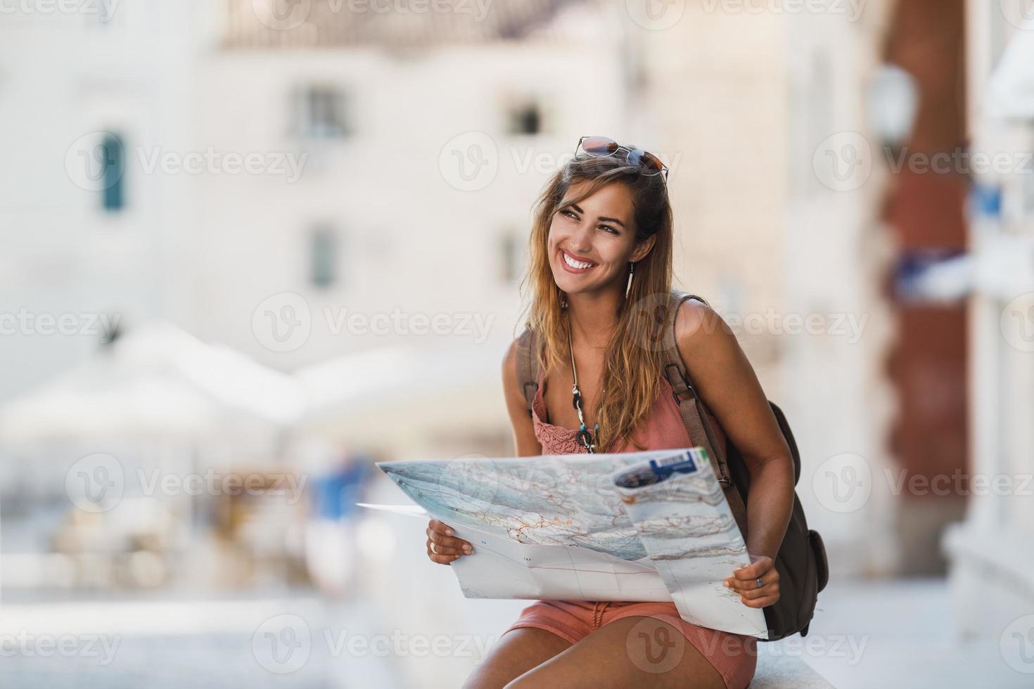 Frau mit einer Karte, die eine fremde Stadt erkundet, während sie die Sommerferien genießt foto