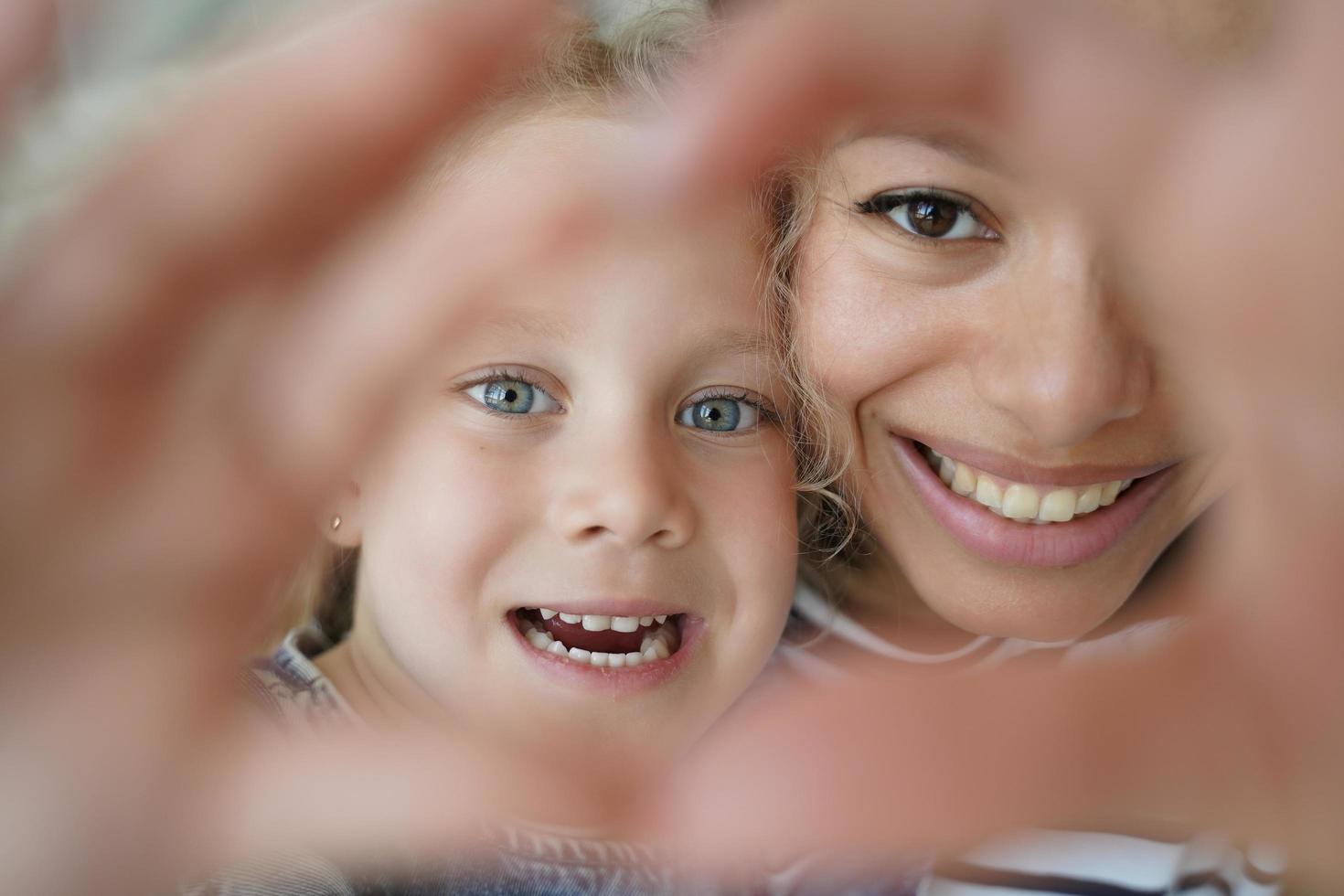 adoptierte tochter, mutter, die zusammen herzgeste zeigt, symbol der liebe, sorge, unterstützung. glückliche Annahme foto