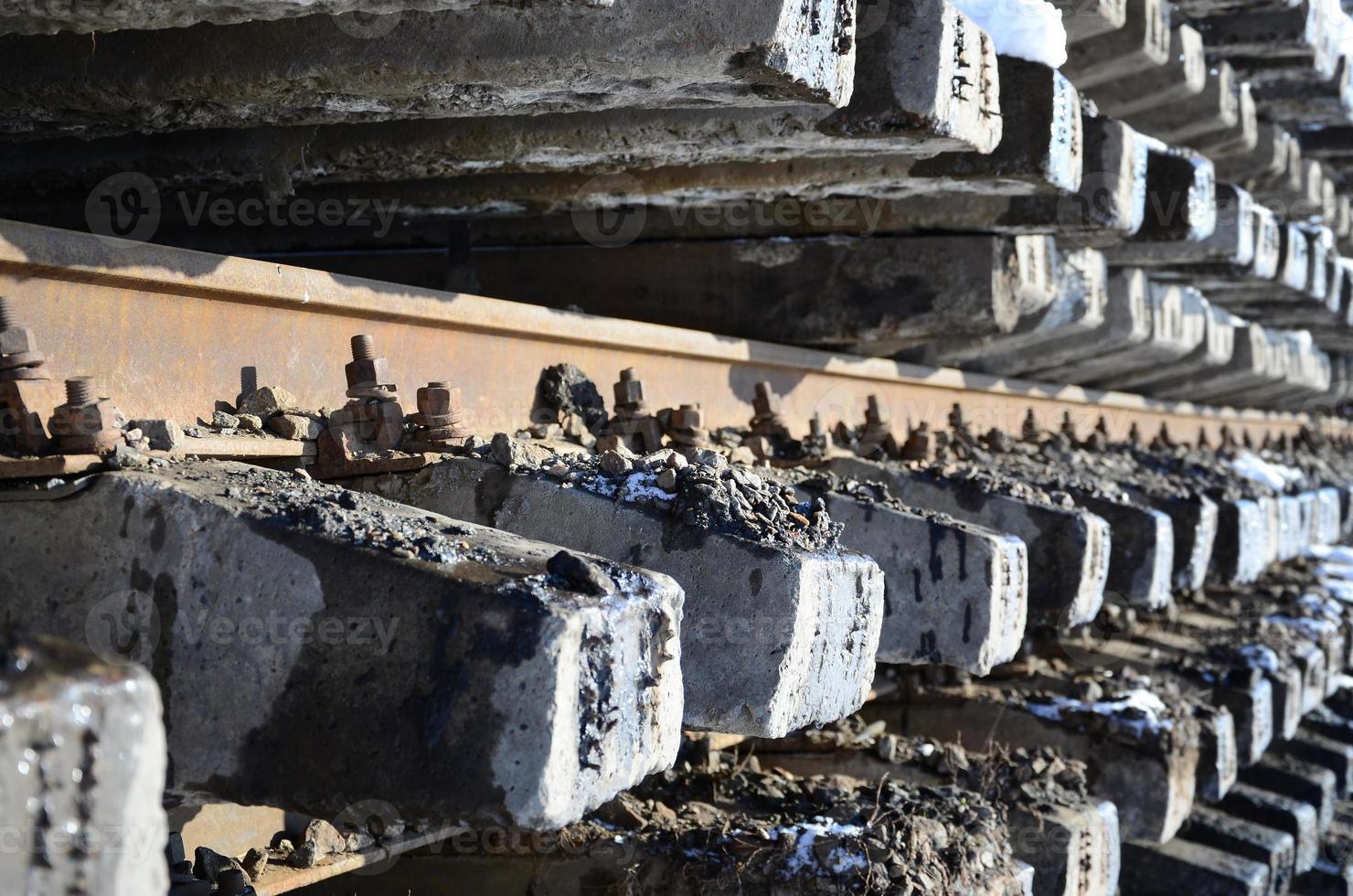 Viele alte Schienen und Schwellen werden im Winter in einem Eisenbahnlager gestapelt. das Konzept, eine abgenutzte Eisenbahnstrecke zu erneuern foto