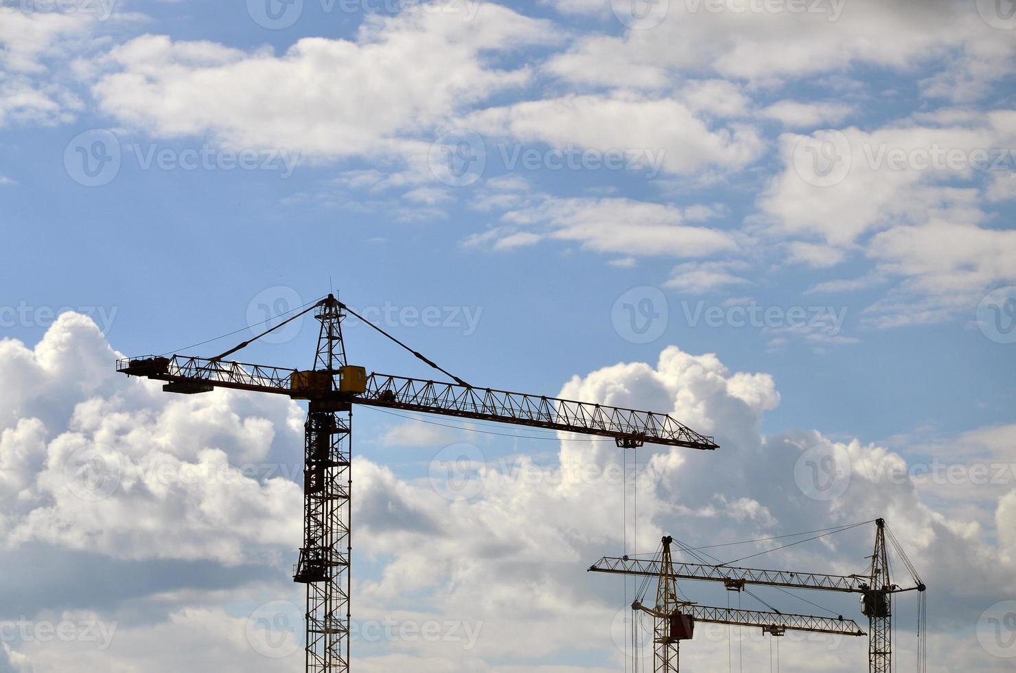 Hohe und schwere Baukrantürme vor blauem Himmel foto