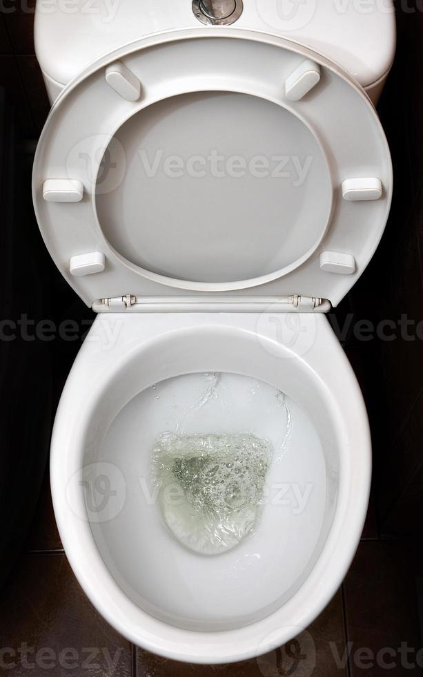 ein Foto einer weißen Keramik-Toilettenschüssel beim Abwaschen. Keramik-Sanitärartikel zur Korrektur des Bedarfs mit einer automatischen Spülvorrichtung