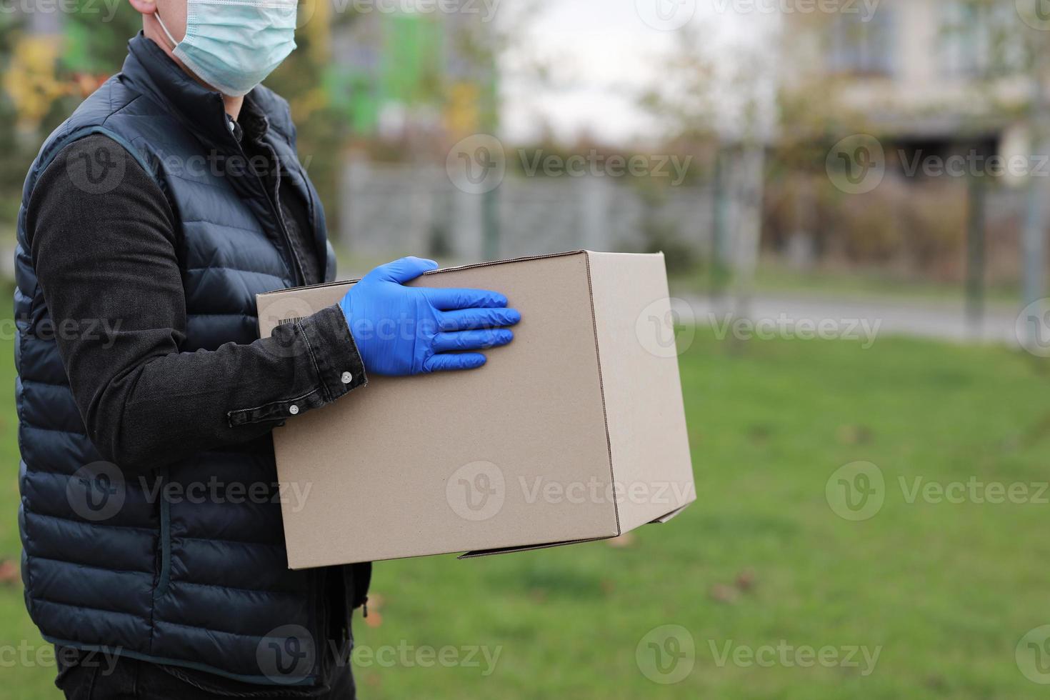 lieferbote mit medizinischer gesichtsmaske, handschuhe halten leere pappschachtel im freien. Service-Coronavirus. Online Einkaufen. Attrappe, Lehrmodell, Simulation. foto