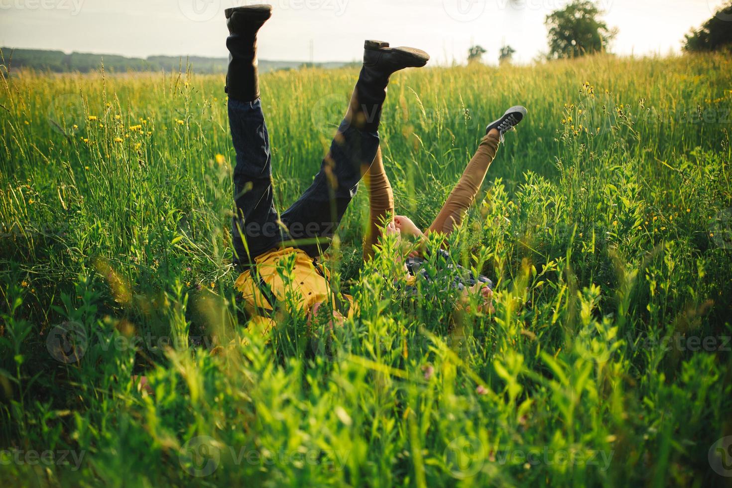 frau und mann haben spaß im freien. Liebendes Hipster-Paar, das auf dem Feld spaziert, sich küsst und Händchen hält, sich umarmt, im Gras liegt und im Sommer bei Sonnenuntergang die Beine hochhebt. Valentinstag foto