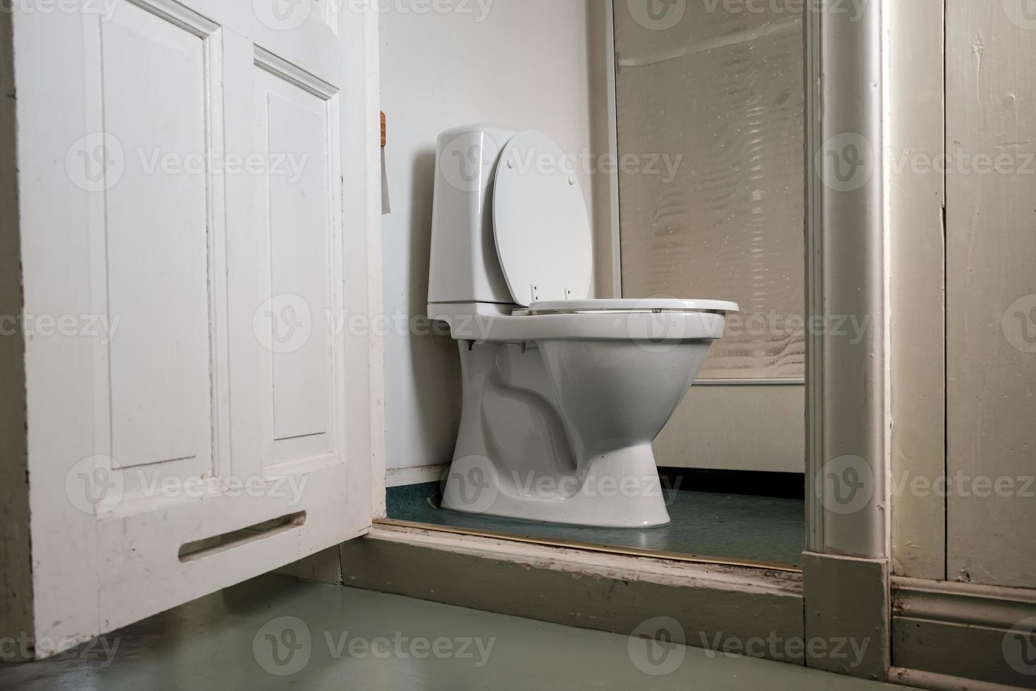 Toilettenschüssel mit Spülkasten und Dusche im Badezimmer, in einem billigen Hotelzimmer. foto