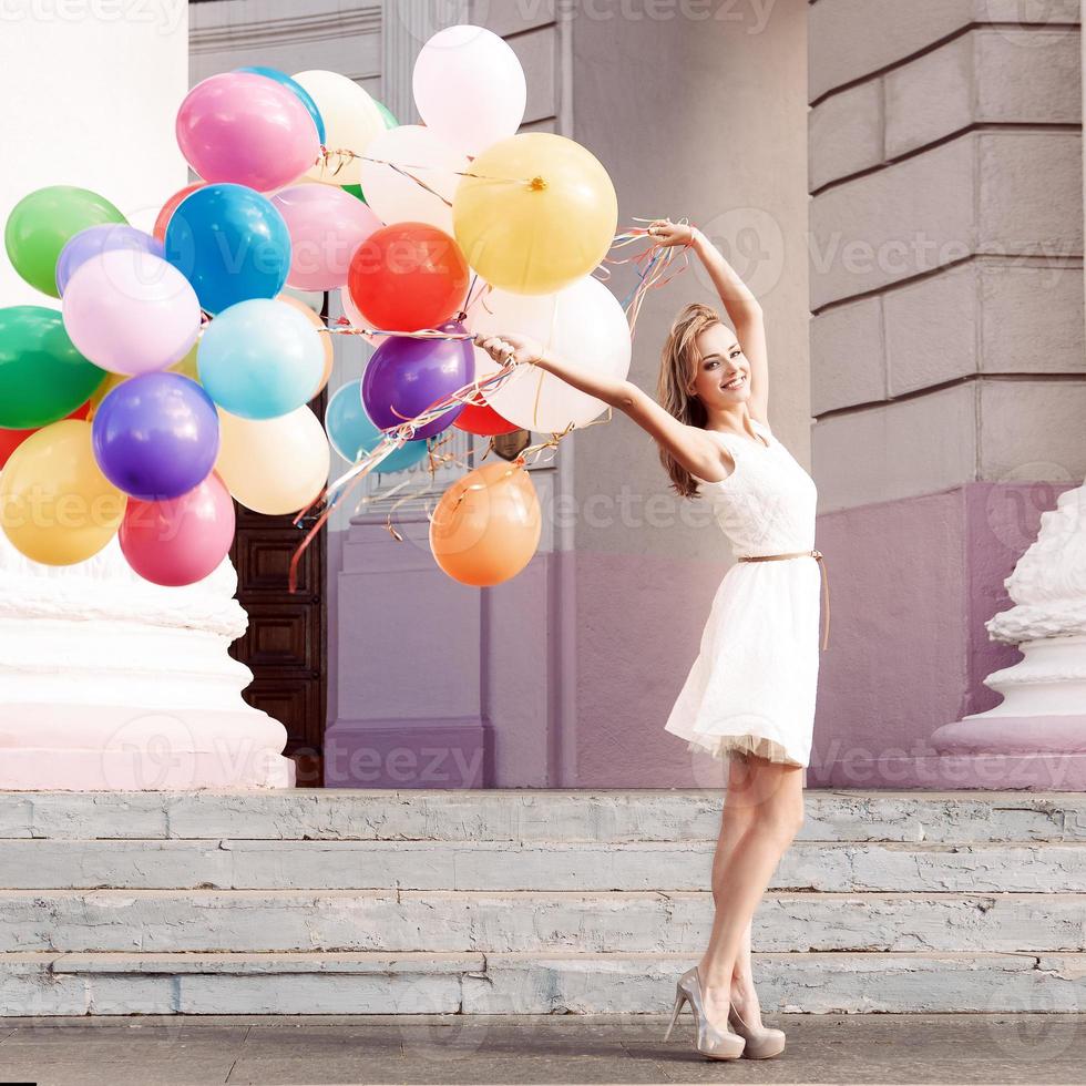 schöne Dame, die ein Bündel Luftballons hält foto